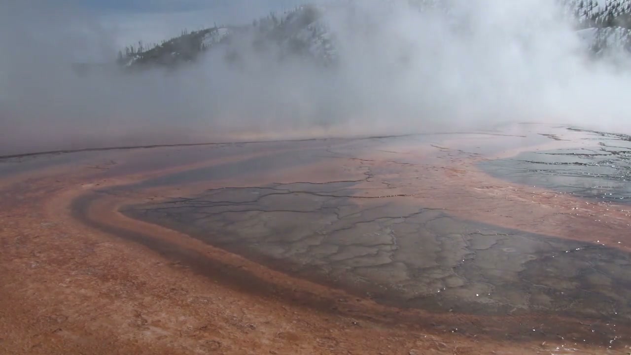 Steam above the orange and turquoise geothermal landscape of Grand Prismatic Spring in Yellowstone.